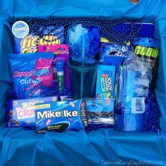 a blue box filled with lots of different types of snacks and candys on top of a table