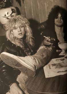 an old black and white photo of two people sitting at a table