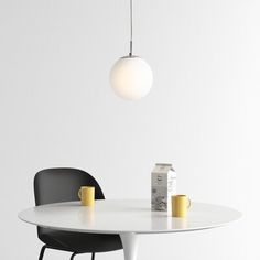 a white table with two black chairs and a light hanging from it's ceiling