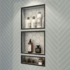 two shelves with bottles and soaps on them in the corner of a room that has herringbone wallpaper