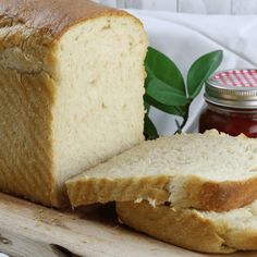 a loaf of bread sitting on top of a cutting board next to a jar of jam