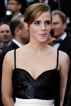 a woman in a black and white dress standing on a red carpet with people behind her