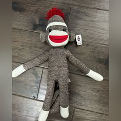 a sock monkey with red hair is laying on the floor