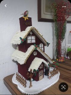 a gingerbread house decorated with icing and decorations on top of a wooden table