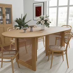 a dining room table with four chairs and a vase on the table in front of it