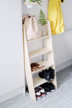 a wooden shelf with shoes on it next to a coat rack