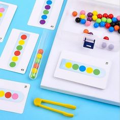 several different colored objects are displayed on a blue table with white trays and plastic markers