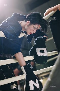 a man leaning on the edge of a boxing ring with his hand in his mittens