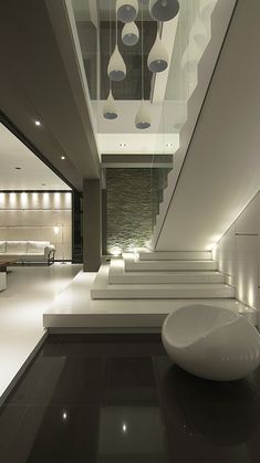 the interior of a modern house with white furniture and lights on the ceiling is lit by recessed lighting