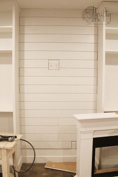 a room with white painted walls and a fireplace in the center, surrounded by shelves