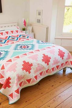 a bed with a colorful quilt on top of it in a room next to a window