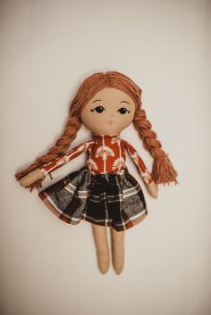 a doll with red hair wearing a black and white dress is hanging on the wall