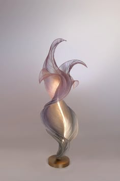 a glass sculpture on a metal stand with a white and pink swirly design in the center