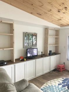 a living room filled with furniture and bookshelves on top of wooden shelves next to a window