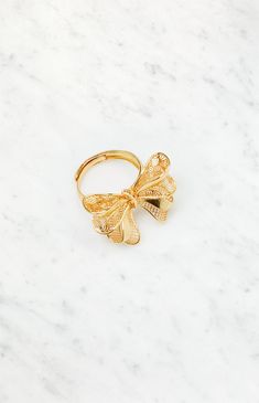 Embrace understated elegance with the LA Hearts Gold Bow Ring, a charming accessory that effortlessly ties together sophistication and style. The delicate gold bow design adds a touch of femininity to your fingers, making this ring the perfect finishing touch for both everyday wear and special occasions.


	Large bow design
	Adjustable band
	Gold finish Chic Yellow Gold Jewelry With Bow Detail, Chic Yellow Gold Jewelry With Bow, Gold Wedding Jewelry With Butterfly Knot Detail, Elegant Yellow Gold Plated Flower Ring, Elegant Gold Jewelry With Butterfly Knot, Elegant Butterfly Knot Jewelry For Wedding, Gold Flower Ring For Party, Gold Elegant Flower Ring For Promise, Elegant Gold Flower Ring As Promise Ring