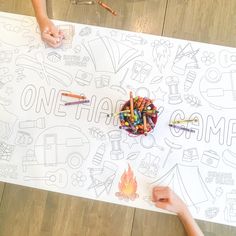 two children are drawing with crayons on a large sheet of paper that says camp