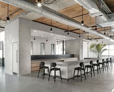 two women are sitting at the counter in an open office with concrete walls and flooring