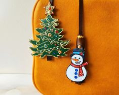 an orange purse with a christmas tree and snowman charm on the front, hanging from it's side