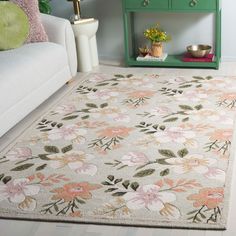 a living room with a white couch and flower rugs on the floor in front of a green cabinet