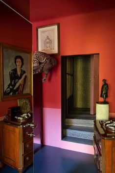 a room with red walls and blue carpeted flooring, painted in different colors