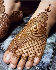 the hands and feet of a woman with henna designs on their palms, both showing