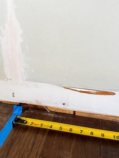 a measuring tape is on the floor next to a wall that has been stripped off