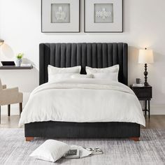 a bed with two framed pictures above it in a white and black bedroom setting on the floor