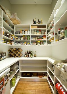 an organized pantry with white shelving and wooden flooring