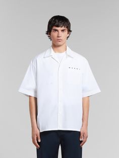 Short-sleeved bowling shirt made from organic cotton poplin. Detailed with a Marni logo poking out from behind the chest pocket. Boxy fit with straight-cut hem and mother-of-pearl button closure. Can be worn with a bowling collar or fully buttoned up. Modern White Short Sleeve Cotton Shirt, Modern White Cotton Short Sleeve Shirt, Modern White Collared Short Sleeve Shirt, Flat Heel Boots, Trunk Bag, Bowling Shirts, Lacing Sneakers, Women Essentials, Mother Of Pearl Buttons