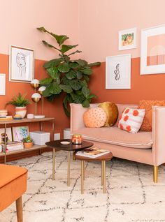 an orange and pink living room with pictures on the wall, coffee table and couch