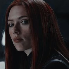 a woman with long red hair is staring into the distance