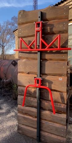 a red metal pole on the side of a wooden building next to a large pipe