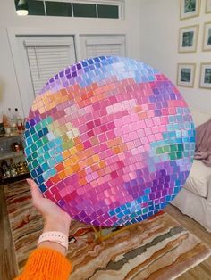 a person holding up a disco ball in their living room