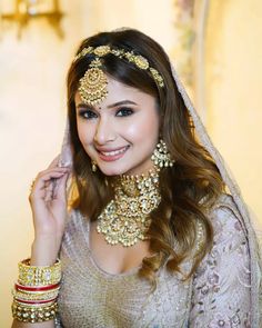 a woman in a bridal outfit posing for the camera with jewelry on her head