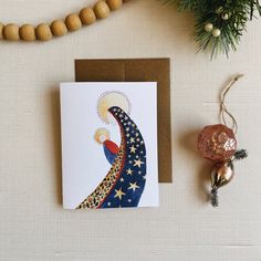 a greeting card with an image of the moon and stars on it next to a christmas ornament