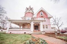 a pink and white victorian style house on a cloudy day