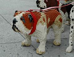 two dogs are made out of legos on the sidewalk, one is brown and white