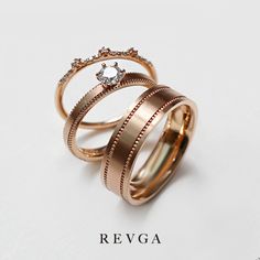 two gold wedding rings with diamonds on top and the words revga written below them