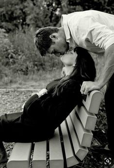 a man and woman kissing on a bench