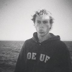 a young man standing in front of the ocean