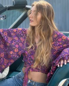 Feel like free spirited hippie queen every day in this versatile floral wrap top. Featuring a vibrant floral pattern, this beautiful top is perfect for all occasions. This top can be worn open, tied in the front, or wrapped and tied in the back making it as versatile as it is fabulous! The wide bell sleeves are reminiscent of 70s style, with a ruffled hem added for flair. The buttery soft and lightweight fabrication is guaranteed to make you feel as good as you look. Whether you wear this top to Summer Hippie V-neck Top, Vintage V-neck Top With Boho Print, Purple Tops For Fall Vacation, Purple Fall Tops For Vacation, Casual Purple Tops For Fall Vacation, Bohemian Pink Top With Vibrant Print, Summer Bohemian Tops With Vibrant Print, Bohemian Long Sleeve Top With Vibrant Print, Purple Floral Print Summer Top