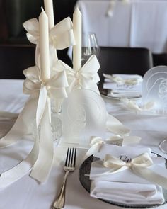 the table is set with white napkins, silverware and candles for an elegant wedding reception