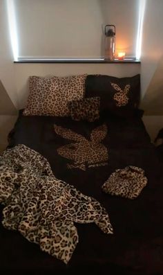 a leopard print comforter and matching pillows on a bed with a lit candle in the corner