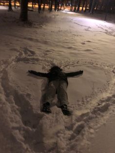 a person laying in the snow with their arms spread out to form a heart shape