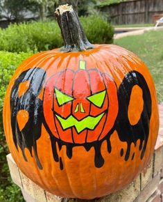 a painted pumpkin sitting on top of a wooden fence