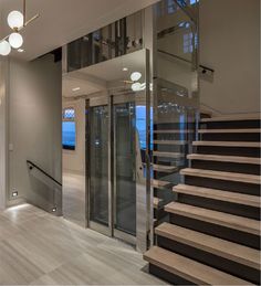 a staircase leading up to the top floor of a house with glass doors and railings