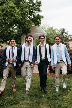 three men in suits and ties are walking through the grass