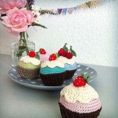 there are three cupcakes on the plate and one is decorated with strawberries