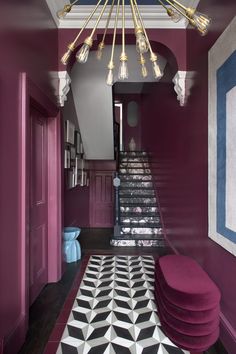 a hallway with pink walls, black and white flooring and a chandelier hanging from the ceiling