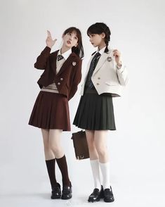 two young women dressed in school uniforms posing for the camera with one pointing at her head